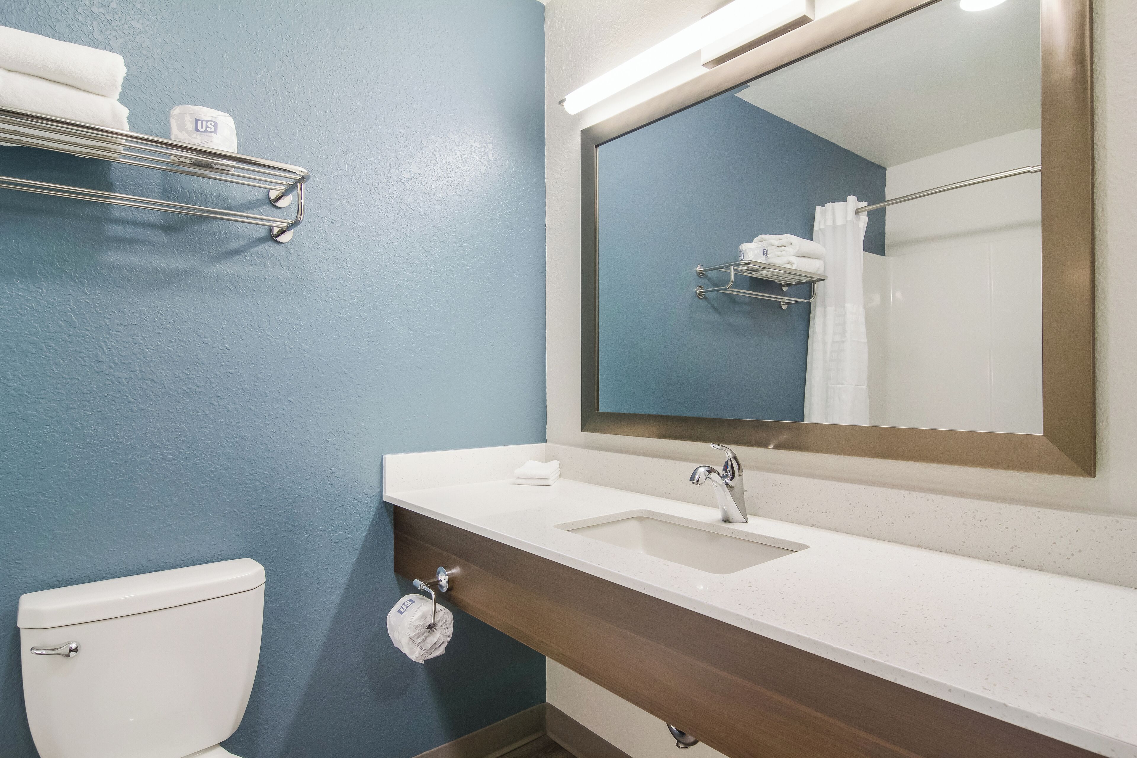 A bathroom with a white sink, a mirror, a towel rack, and a toilet.