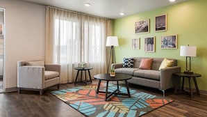 Una sala de estar moderna con sofá, sillón, mesa de centro y dos mesitas auxiliares.