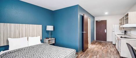 A hotel room with a bed, a desk, and a kitchenette.