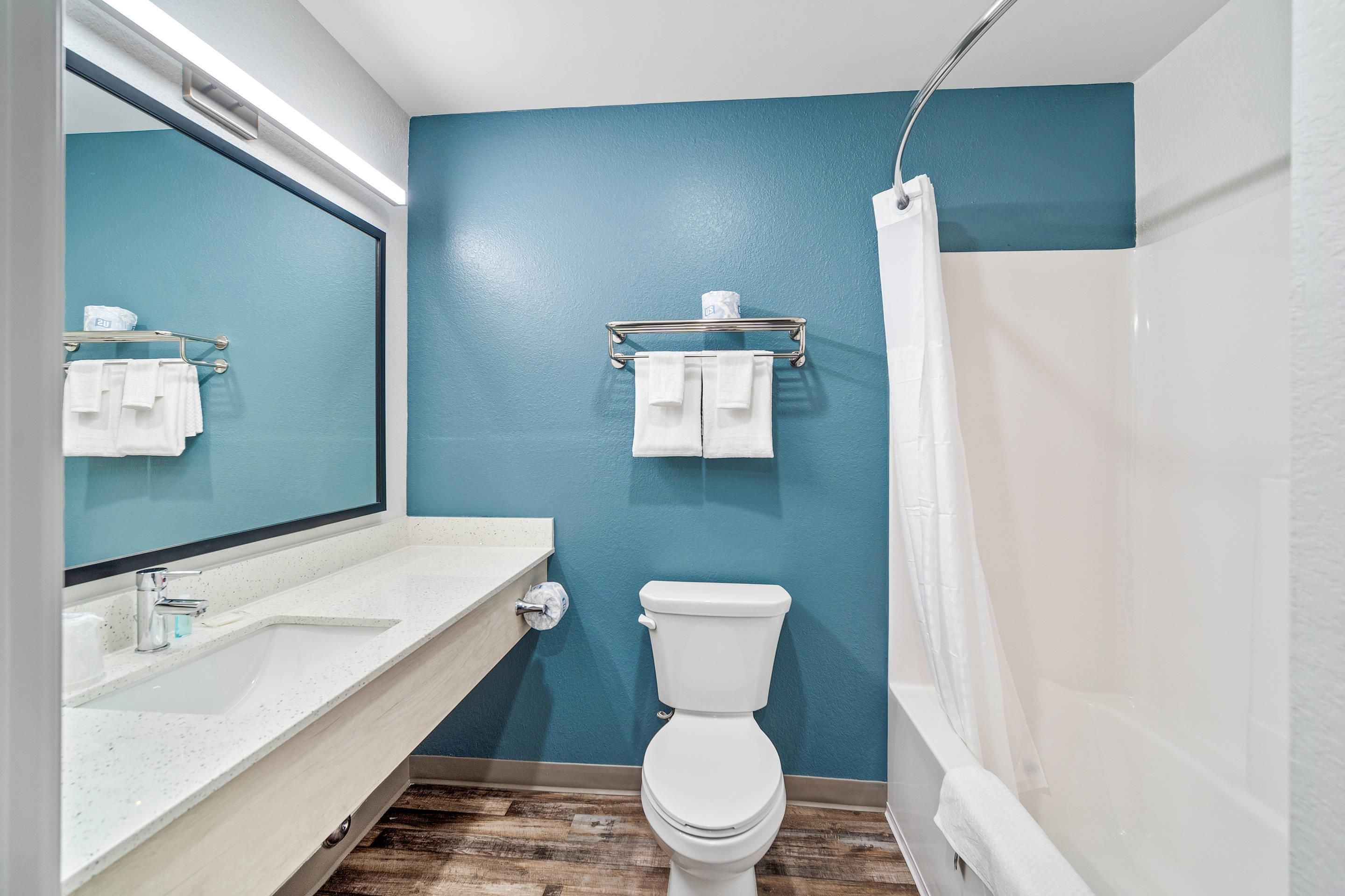 Un baño con pared azul, lavabo blanco y retrete.