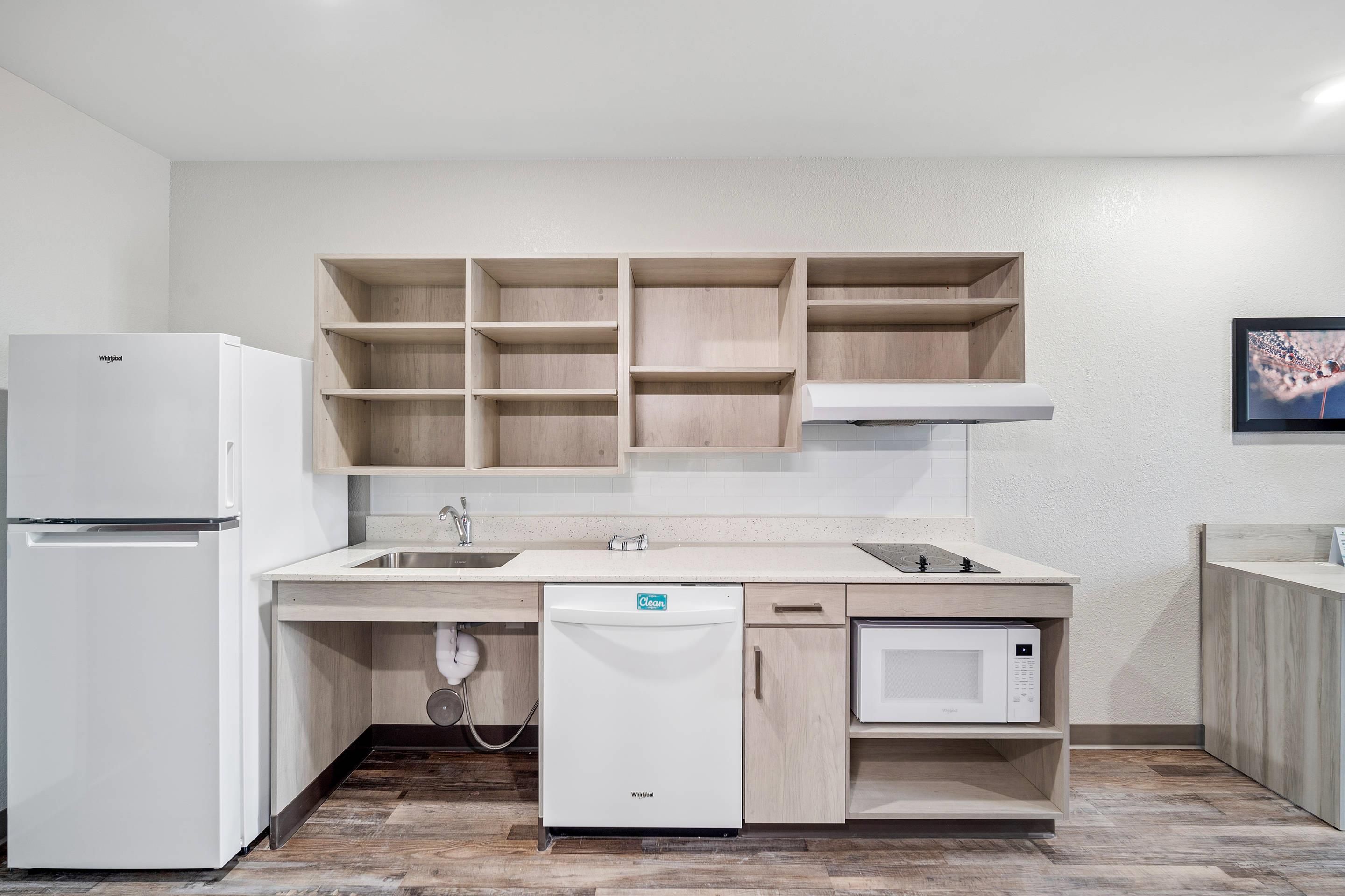 A modern kitchen with a built-in dishwasher, a refrigerator, and wooden cabinets.