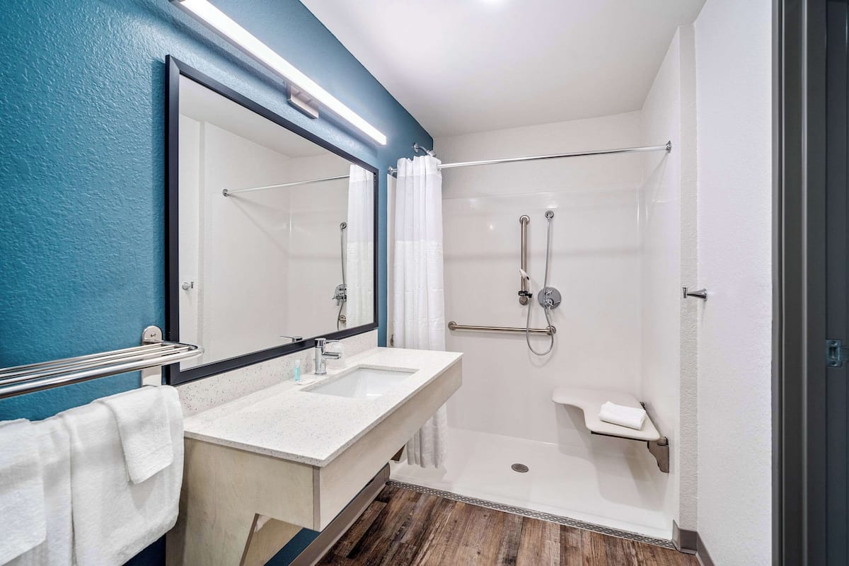 Une salle de bain moderne avec un grand miroir, deux lavabos, une douche et un porte-serviettes.