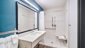 Une salle de bain moderne avec un grand miroir, deux lavabos, une douche et un porte-serviettes.
