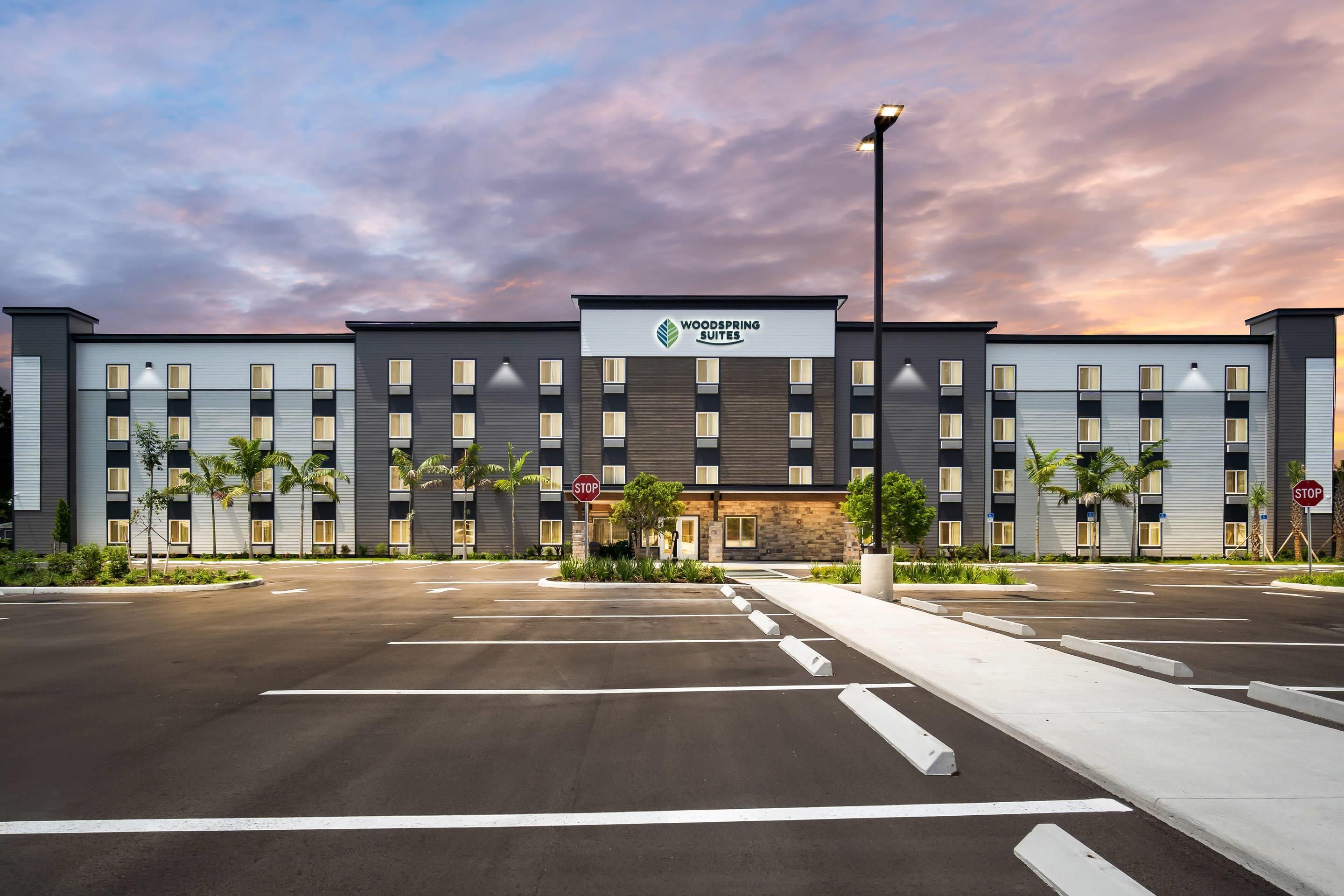 Ein modernes Hotel mit flachem Dach, zahlreichen Fenstern und einem Schild mit der Aufschrift 'Woodspring Suites'.