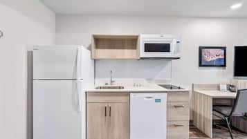 A compact kitchen with a refrigerator, microwave, sink, and dishwasher.