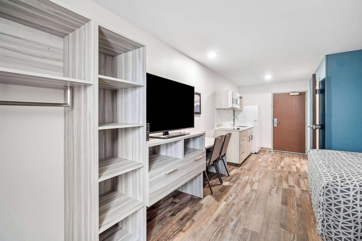 Une chambre d’hôtel moderne équipée d’un bureau intégré, d’une télévision, d’une chaise, d’un lit et d’une armoire.