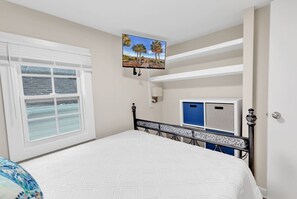 Un dormitorio con cama, ventana con persianas, televisor montado en la pared y un armario azul.