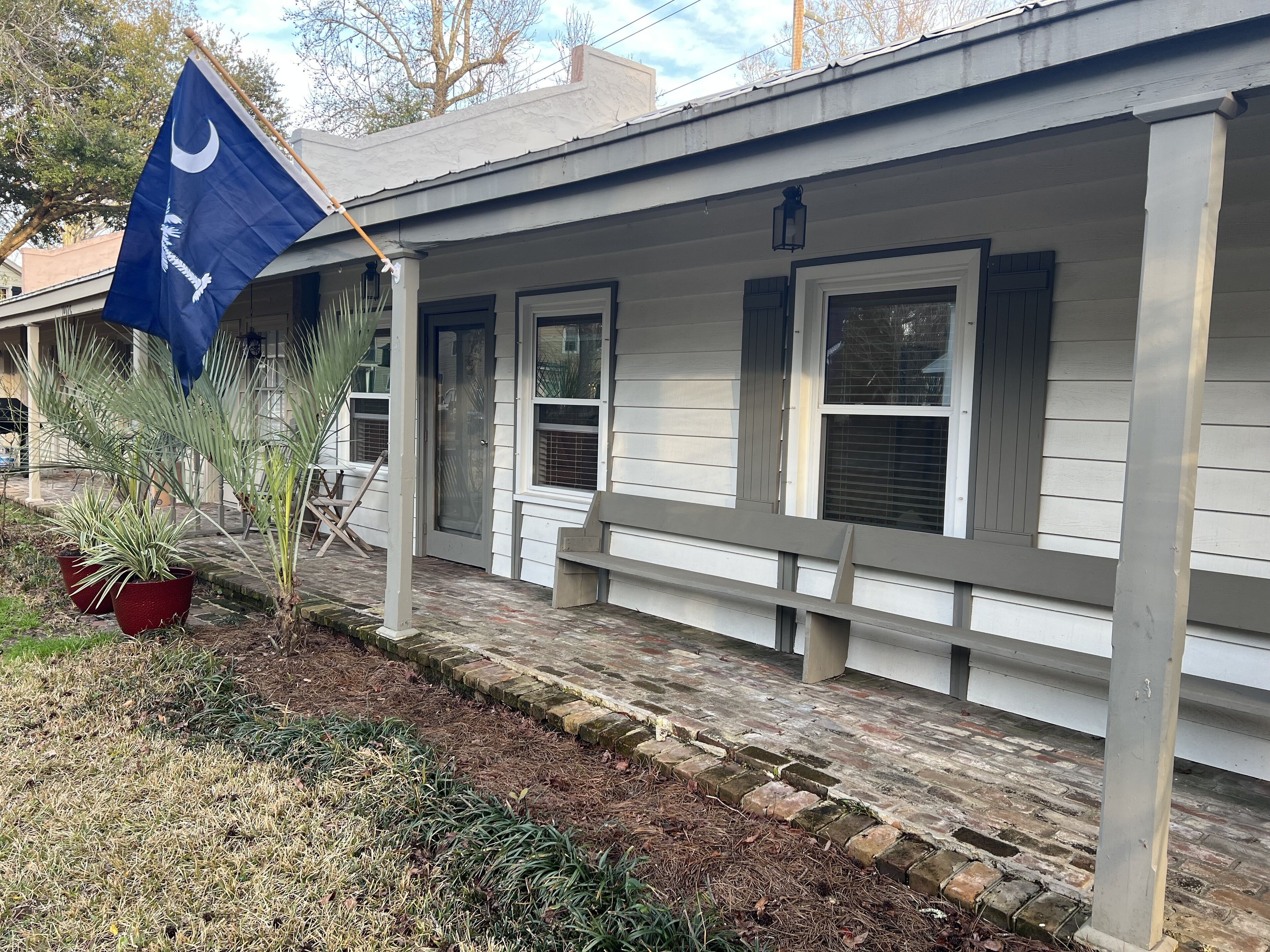 Ein Haus mit Veranda, einer Flagge und Kübelpflanzen.
