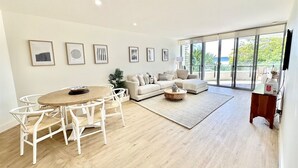 Un salón espacioso con mesa y sillas de comedor, un sofá y un amplio ventanal con vistas al exterior.