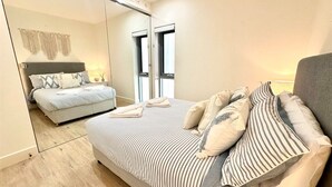 Un dormitorio moderno con una cama grande, un espejo y vistas al mar.
