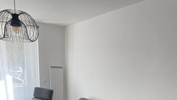 Un salon moderne avec un canapé d’angle gris, un fauteuil foncé et une table basse en bois.