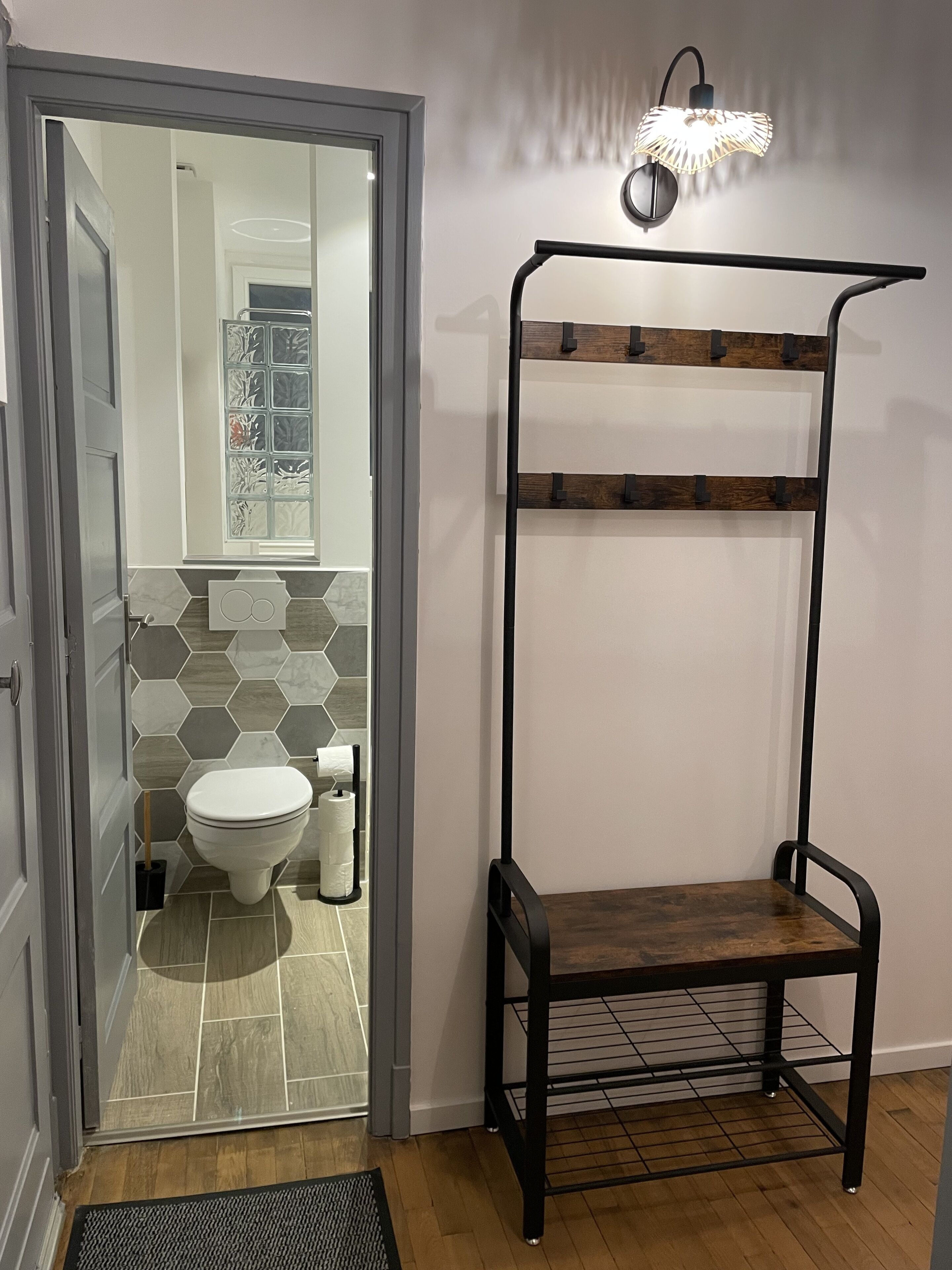 A bathroom with a toilet, a shower, and a sink. There is a mirror above the sink and a towel rack on the wall.