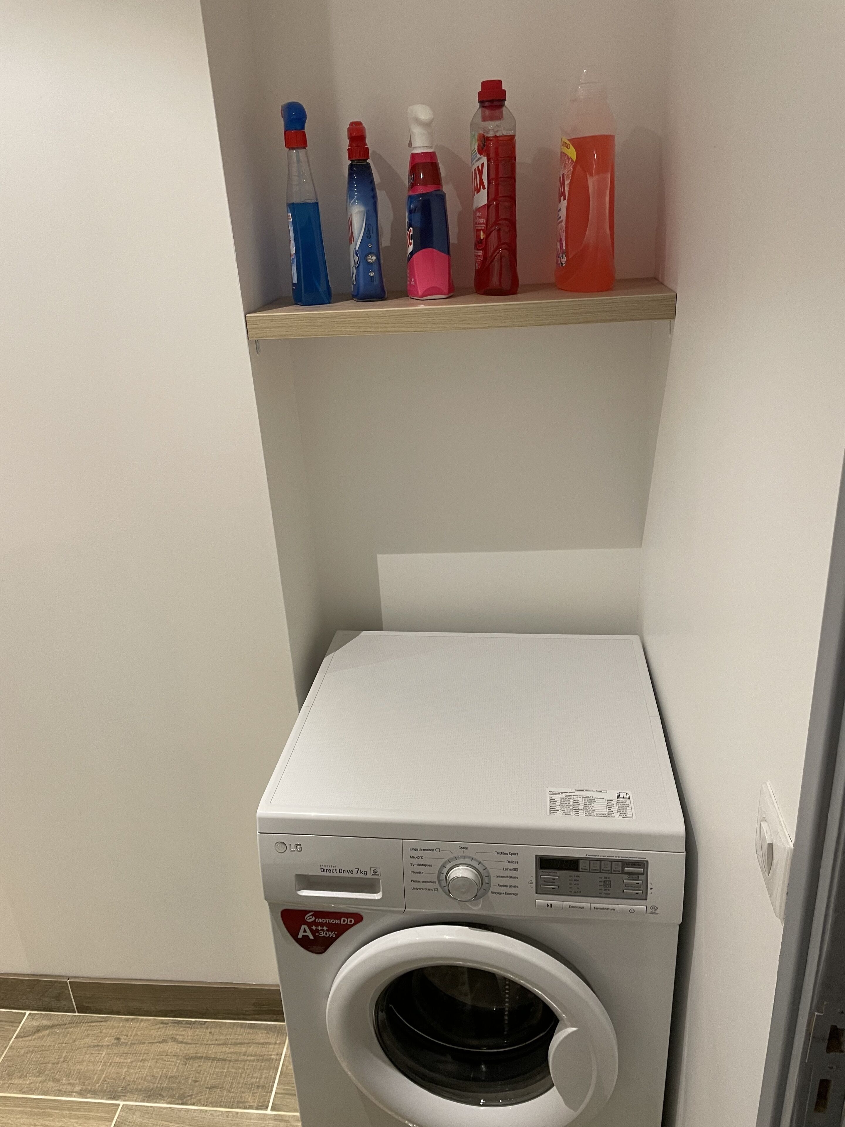 Un lave-linge à chargement frontal doté d’un panneau de commande et d’un compartiment pour la lessive situé au-dessus.