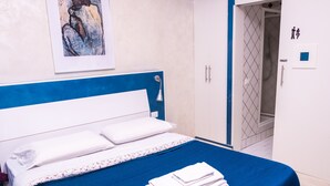 A hotel room with a bed, a blue headboard, a painting, a wardrobe, and a toilet sign. - Romatic Guest House  (Rome)
