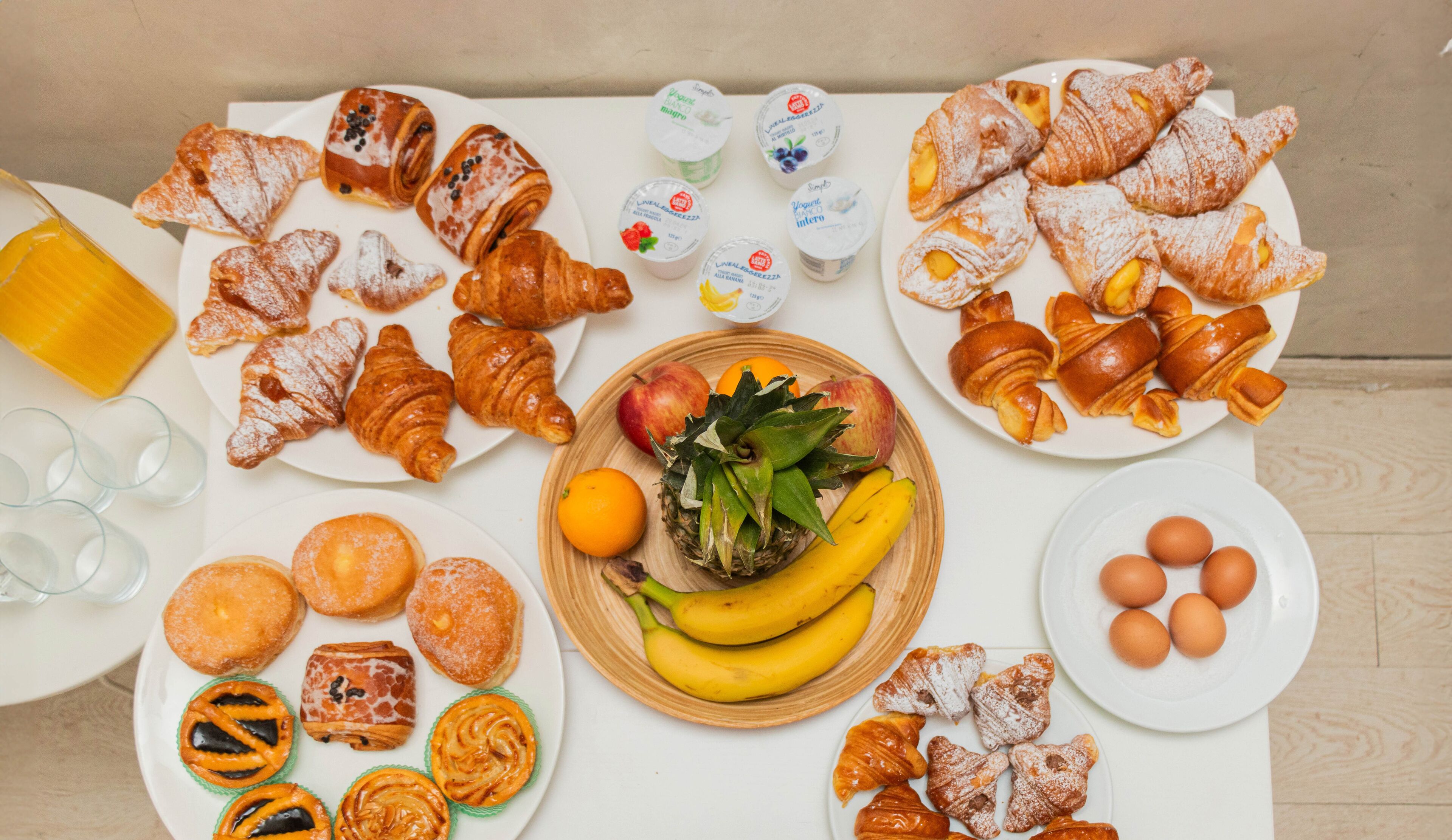 A table with various pastries, fruits, and drinks.