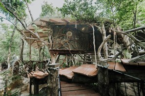 A rustic treehouse structure with a thatched roof, wooden beams, and a rope ladder. - El Sueño Riviera Maya (Tulum)