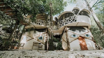 A treehouse with a unique design, featuring circular windows and a thatched roof.