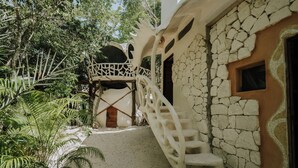 A stone staircase leading to a wooden door, surrounded by lush greenery and a clear sky. - El Sueño Riviera Maya (Tulum)