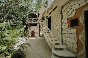 A stone staircase leading to a wooden door, surrounded by lush greenery and a clear sky. - El Sueño Riviera Maya (Tulum)