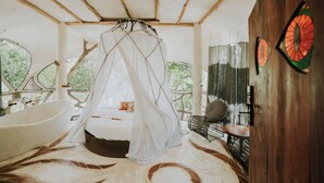 A room with a bed under a canopy, a bathtub, and a large window with a view of greenery. - El Sueño Riviera Maya (Tulum)