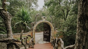A pathway leading to a door with a decorative archway, surrounded by trees and plants. - El Sueño Riviera Maya (Tulum)
