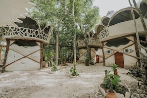 A courtyard with unique treehouse structures, each with a distinct design and surrounded by greenery. - El Sueño Riviera Maya (Tulum)