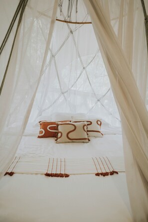 Una estructura tipo tienda de campaña con una cama en su interior, que incluye un dosel y cuerdas.