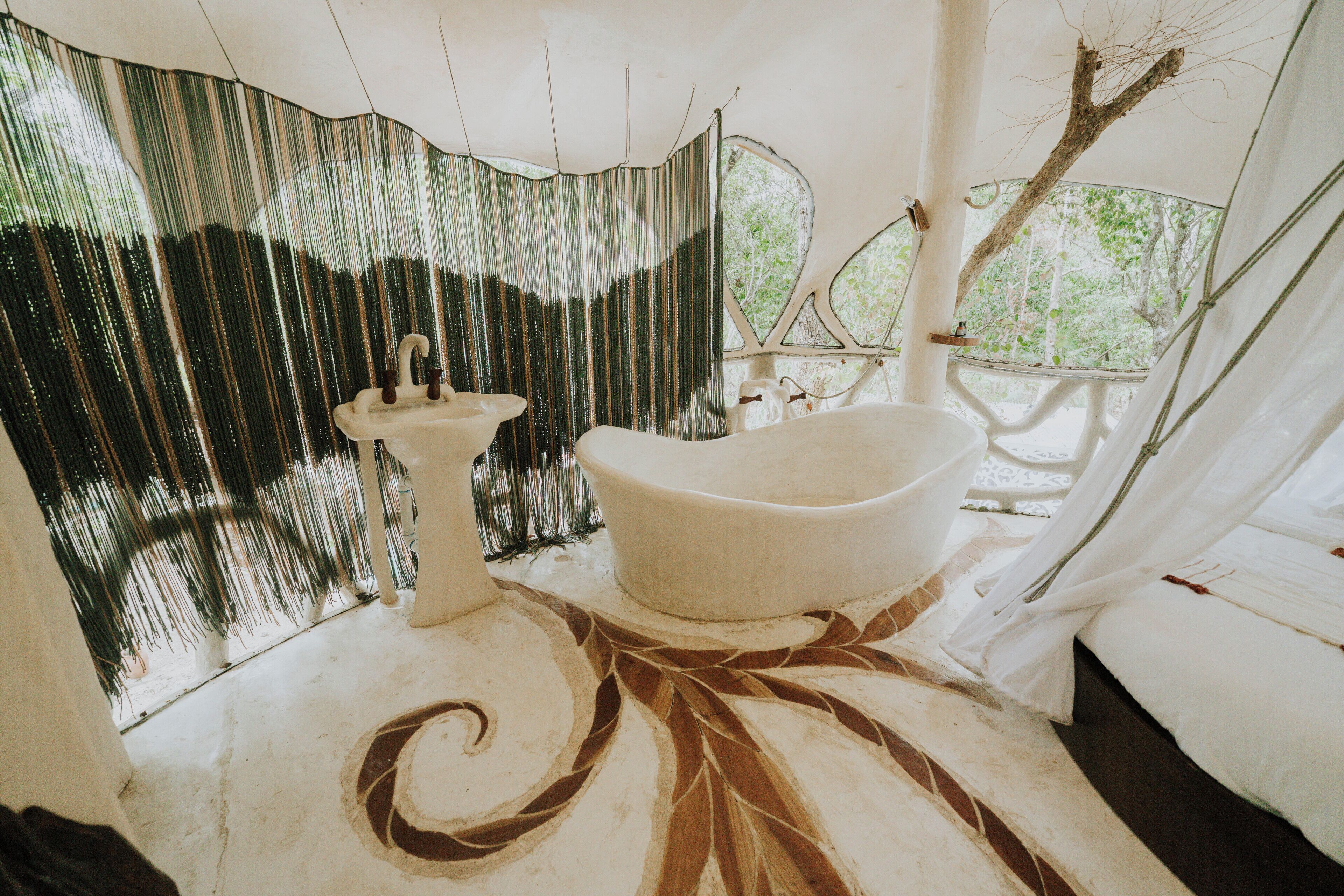 A bathroom with a freestanding bathtub, a pedestal sink, and a decorative floor pattern.