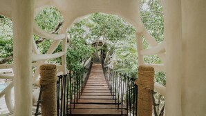 A pathway with a metal railing, surrounded by trees and a white archway structure. - El Sueño Riviera Maya (Tulum)