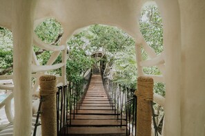 A pathway with a metal railing, surrounded by trees and a white archway structure. - El Sueño Riviera Maya (Tulum)