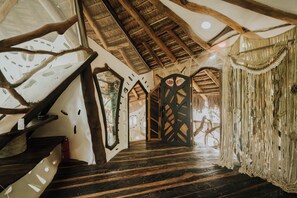 Un interno rustico con una scala in legno, un tetto di paglia e un design di porta unico.