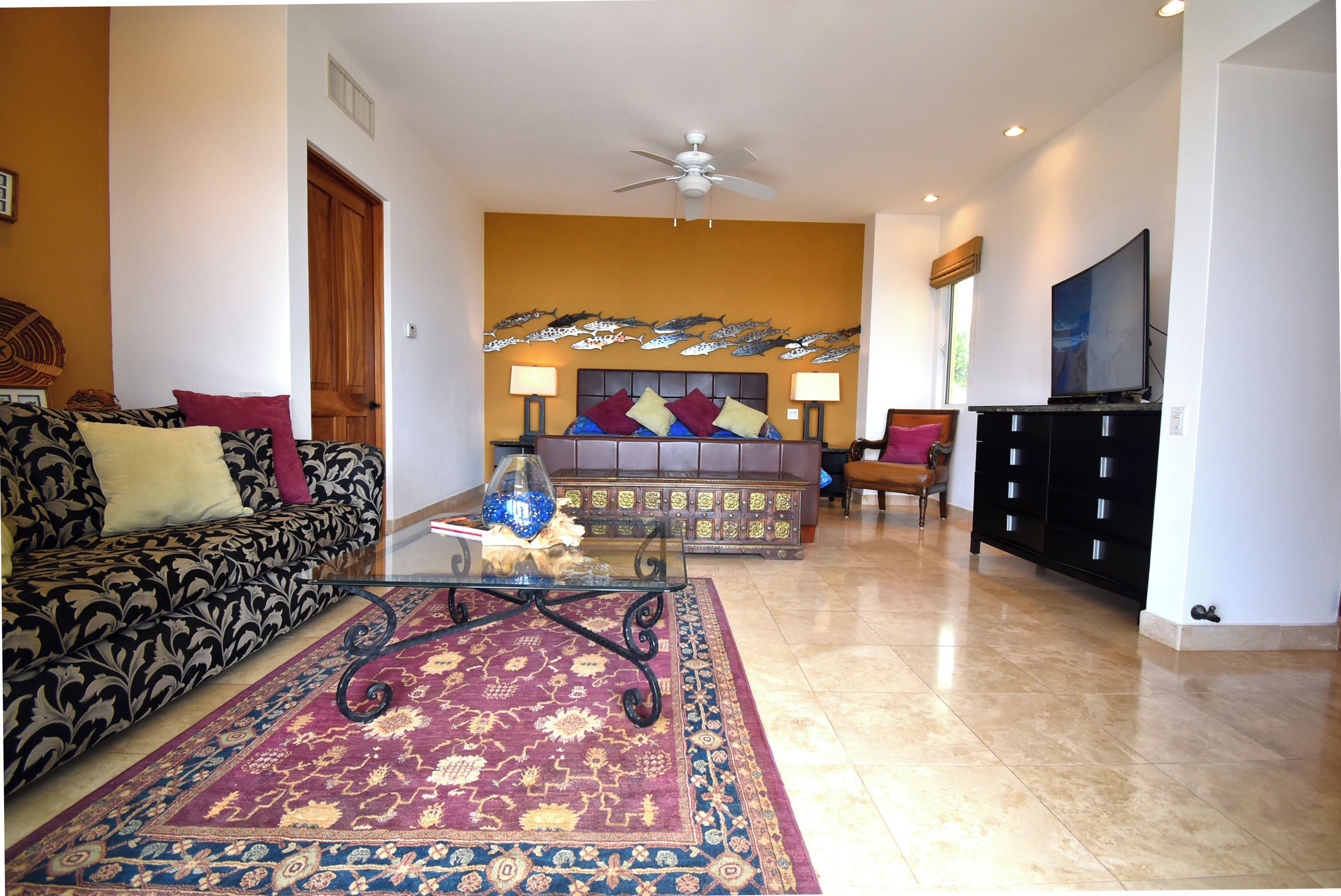 A living room with a sofa, a coffee table, a TV, and a decorative wall.