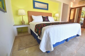 A hotel room with a bed, a nightstand, a lamp, a mirror, and a door.
