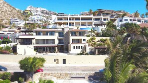 A coastal residential area with multi-story buildings, a swimming pool, and lush greenery.