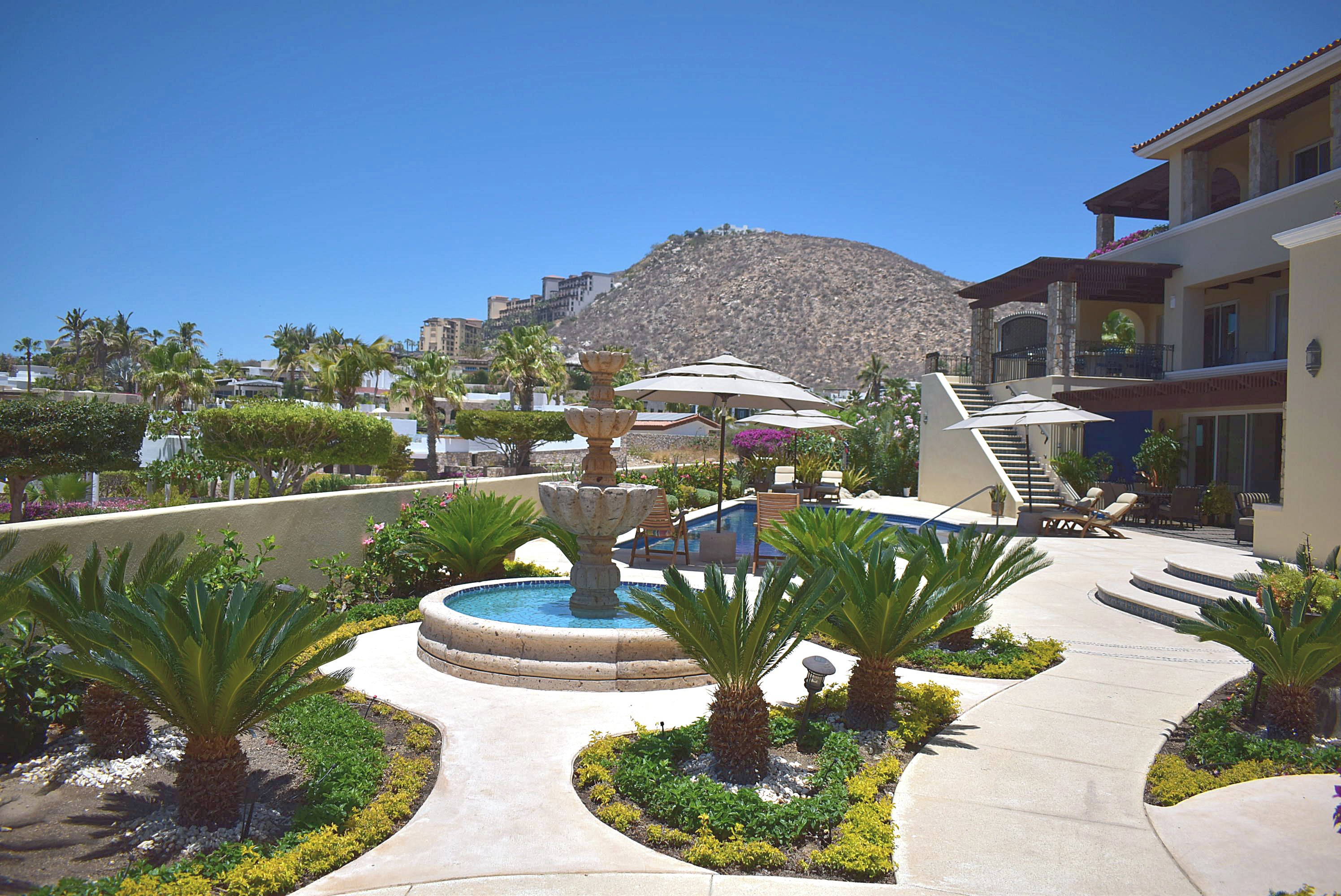A resort with a pool, palm trees, and a mountain in the background.