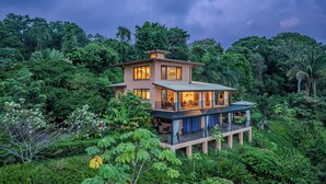 A two-story house surrounded by lush greenery.