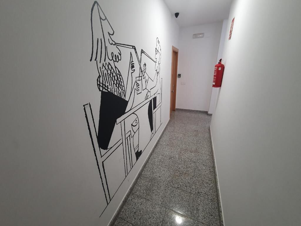 Un pasillo con un extintor en la pared derecha y una puerta al final.