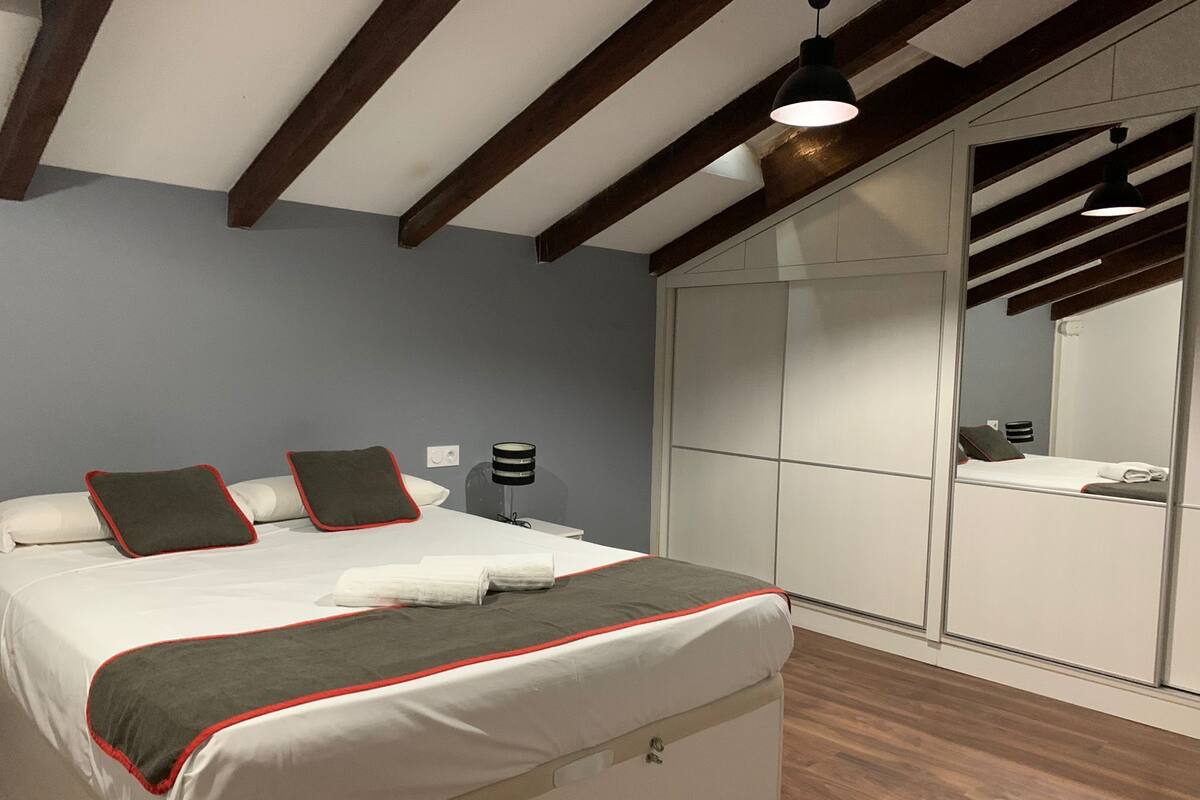 Een moderne slaapkamer met een bed, nachtlampen en een kledingkast.