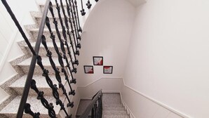 A staircase with a black metal railing and granite steps. There are three framed artworks on the wall to the right. - Luxury Apartments Puerto Valencia (Valencia)