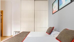 A modern bedroom with a large bed, a wardrobe, and a framed picture on the wall. - Luxury Apartments Puerto Valencia (Valencia)