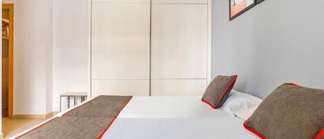 A modern bedroom with a large bed, a wardrobe, and a framed picture on the wall.