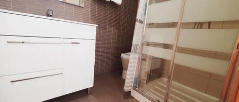 A bathroom with a white vanity, a shower with a glass door, and a toilet.