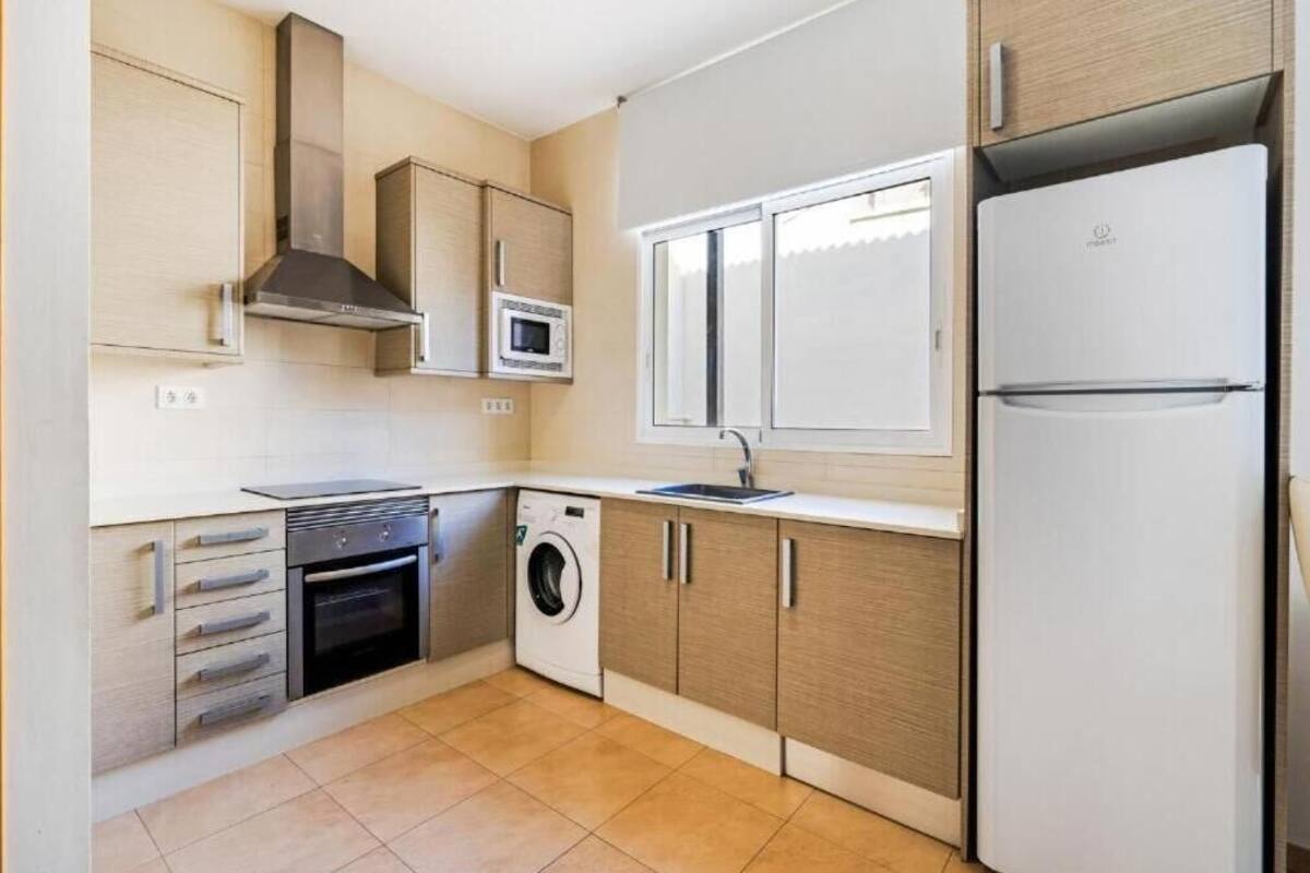 Een moderne keuken met een inbouwoven, magnetron, wasmachine en een grote koelkast.