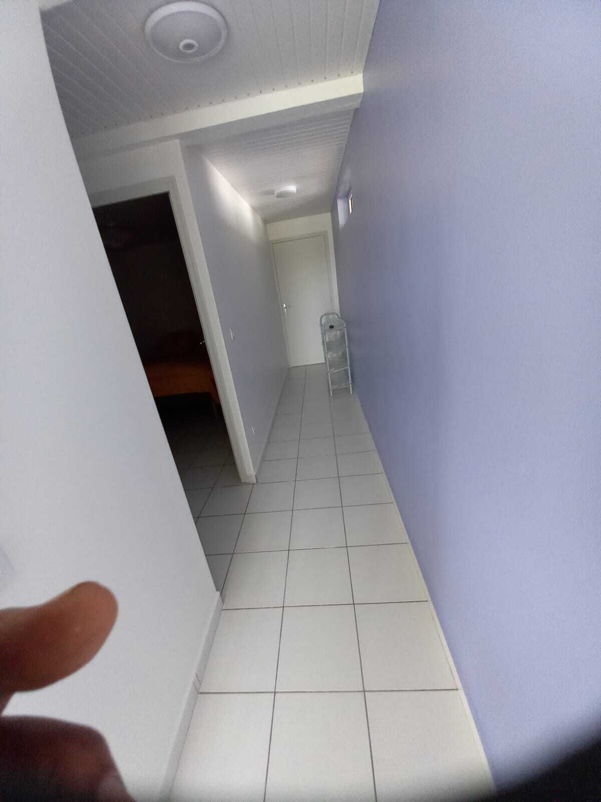 A narrow hallway with white tiled flooring and light blue walls.