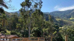 A paved pathway leading to a wooden gate, surrounded by lush greenery and hills in the background. - Cabana I nas Montanhas de Gonçalves (Gonçalves)