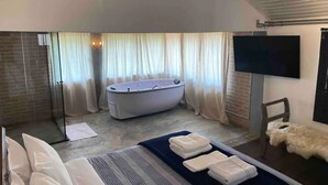 A modern bathroom with a bathtub, a shower, and a flat-screen TV mounted on the wall. - Cabana I nas Montanhas de Gonçalves (Gonçalves)