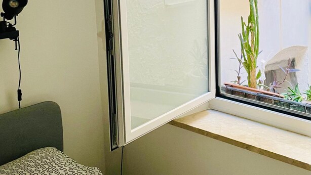 A room with a partially open window, a desk with a lamp, and a patterned cushion. - Nonna Jaca Apartament (Trapani)