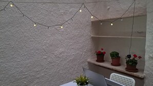 A table with a laptop and a potted plant, surrounded by shelves with potted plants and string lights. - Nonna Jaca Apartament (Trapani)