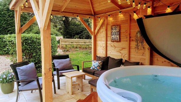 Un belvédère en bois avec un jacuzzi, des sièges d’extérieur et une pancarte sur laquelle on peut lire : « LE BON VIEUX TEMPS ».