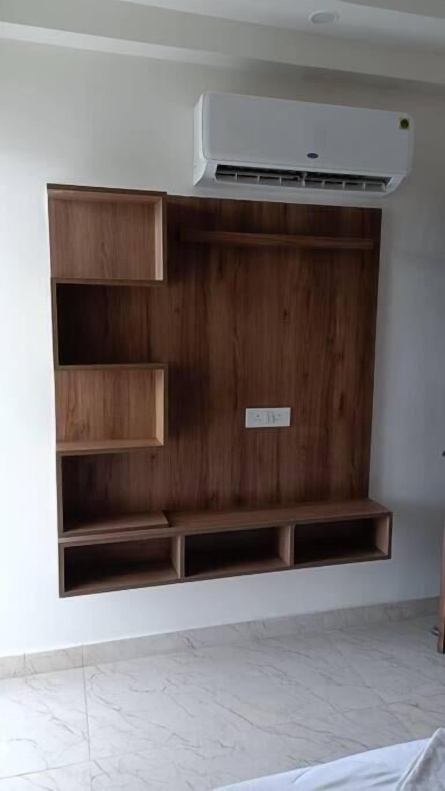 A room with a built-in wooden shelf unit, an air conditioning unit above it, and a tiled floor.
